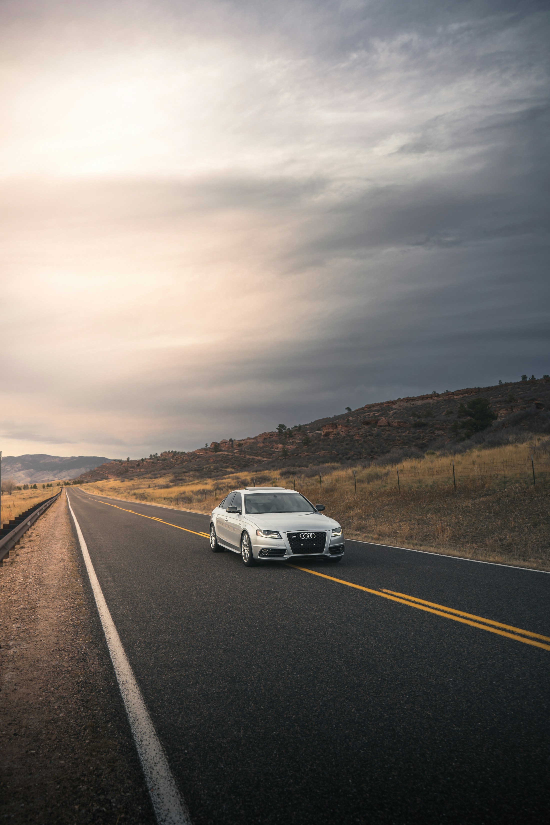 Silver car parked on a quiet country road beneath an overcast sky